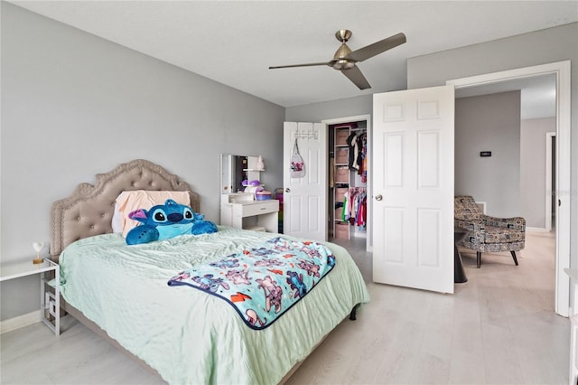 bedroom with a walk in closet, a closet, ceiling fan, and light hardwood / wood-style floors