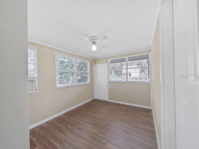 empty room with dark hardwood / wood-style floors, ceiling fan, and crown molding