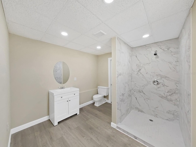 bathroom with tiled shower, hardwood / wood-style floors, vanity, and toilet