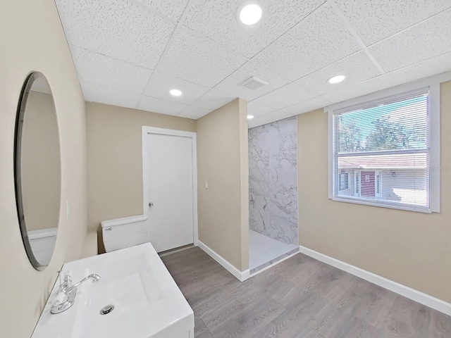 bathroom featuring a shower, sink, wood-type flooring, and a drop ceiling