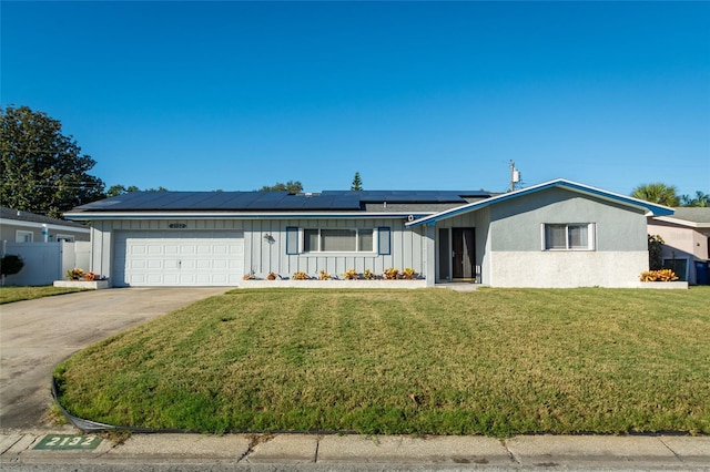 ranch-style house with solar panels, a garage, and a front yard