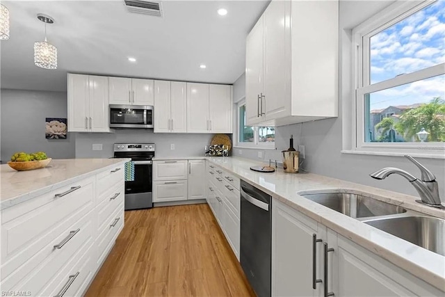 kitchen with white cabinetry, a wealth of natural light, appliances with stainless steel finishes, and hanging light fixtures