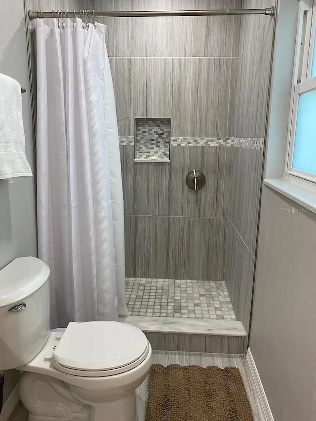 bathroom with a shower with shower curtain and toilet