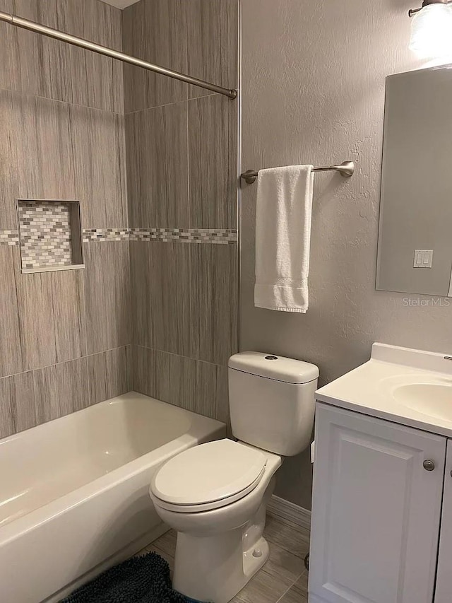 full bathroom featuring toilet, vanity, and tiled shower / bath