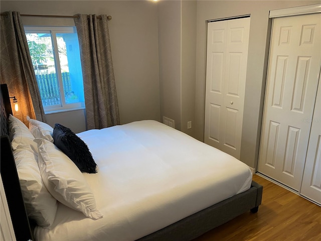 bedroom with hardwood / wood-style flooring and two closets