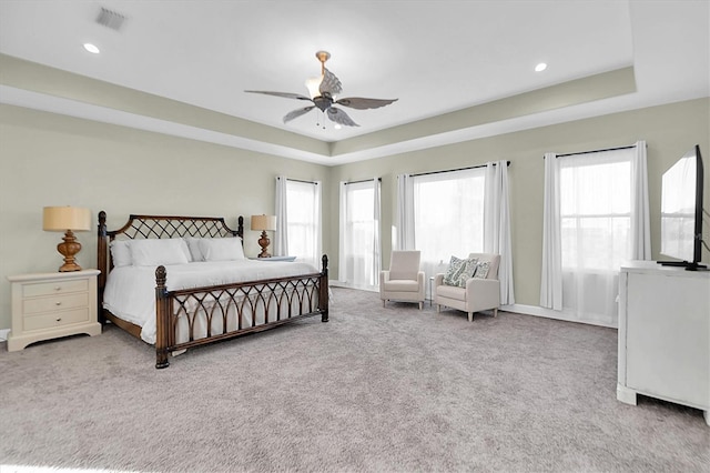 carpeted bedroom featuring a raised ceiling and ceiling fan