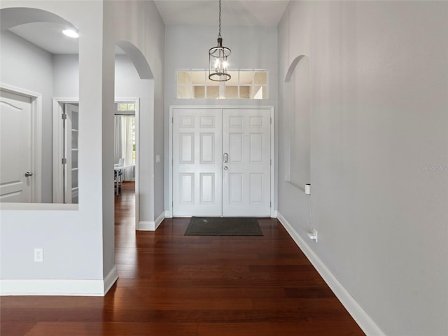 entrance foyer with dark hardwood / wood-style flooring and a notable chandelier