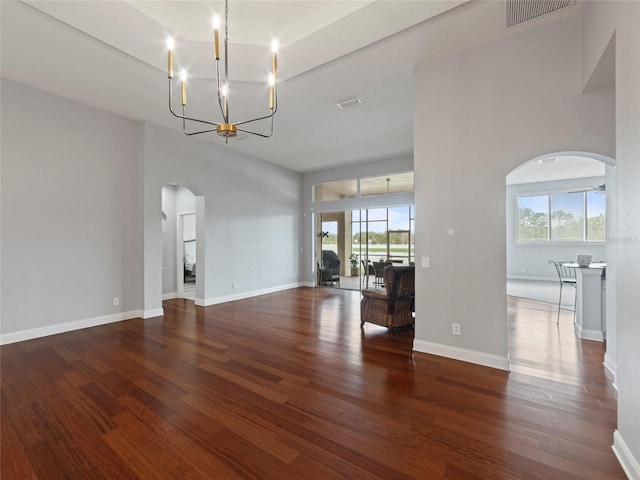 unfurnished living room with a high ceiling, dark hardwood / wood-style flooring, and a notable chandelier