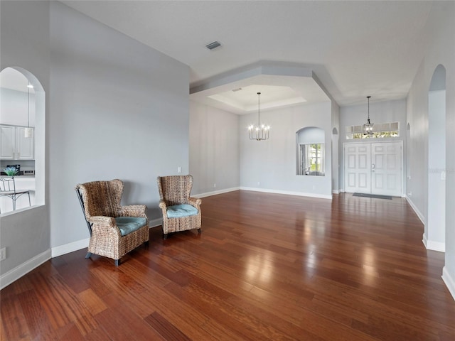 unfurnished room featuring dark hardwood / wood-style flooring, a notable chandelier, and a raised ceiling