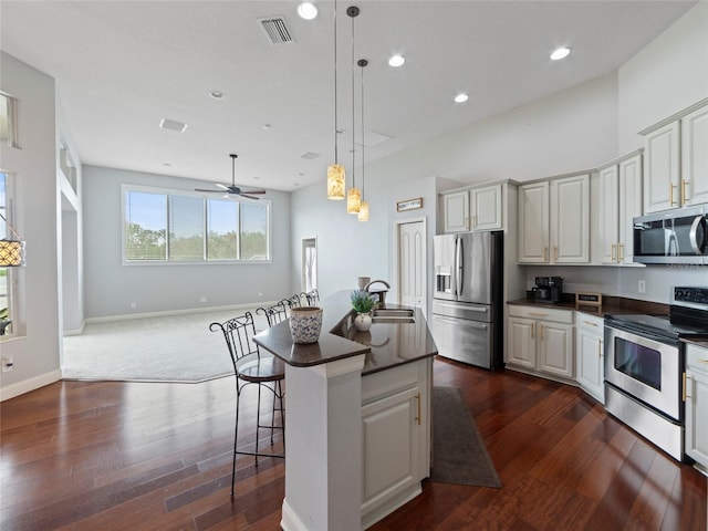 kitchen with stainless steel appliances, decorative light fixtures, a kitchen bar, ceiling fan, and a center island