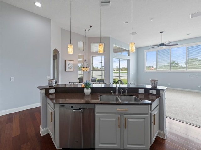 kitchen featuring a kitchen island with sink, dark wood-type flooring, stainless steel dishwasher, and sink