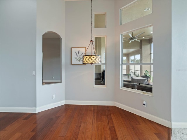 spare room with hardwood / wood-style flooring, ceiling fan, and a towering ceiling