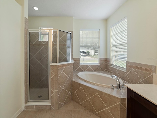 bathroom featuring plus walk in shower, vanity, and tile patterned flooring