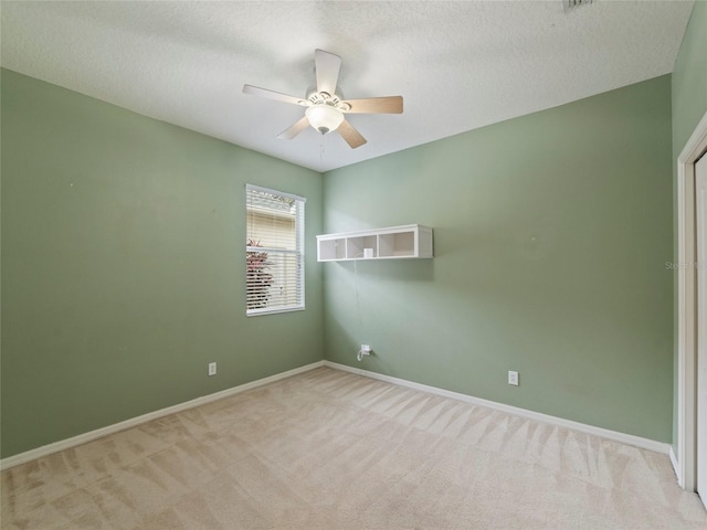 spare room with ceiling fan, a textured ceiling, and light carpet