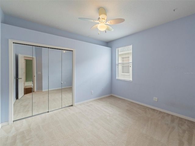 unfurnished bedroom featuring light carpet, ceiling fan, and a closet