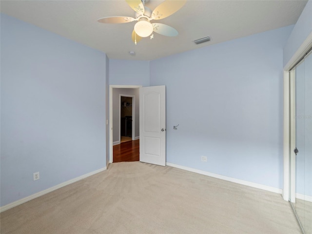 unfurnished bedroom featuring ceiling fan, light carpet, and a closet