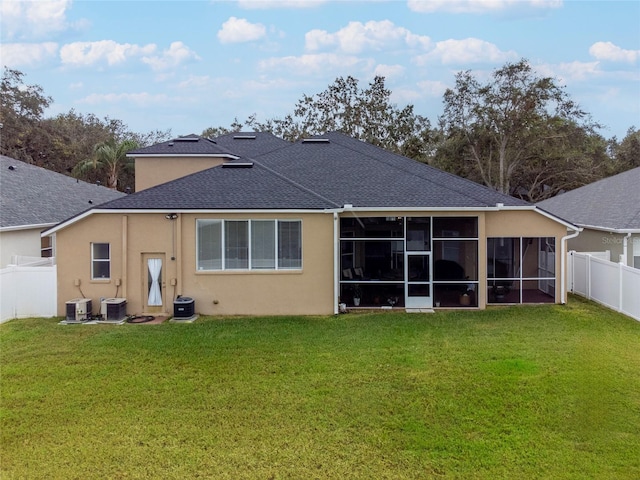 back of property featuring central air condition unit, a lawn, and a sunroom