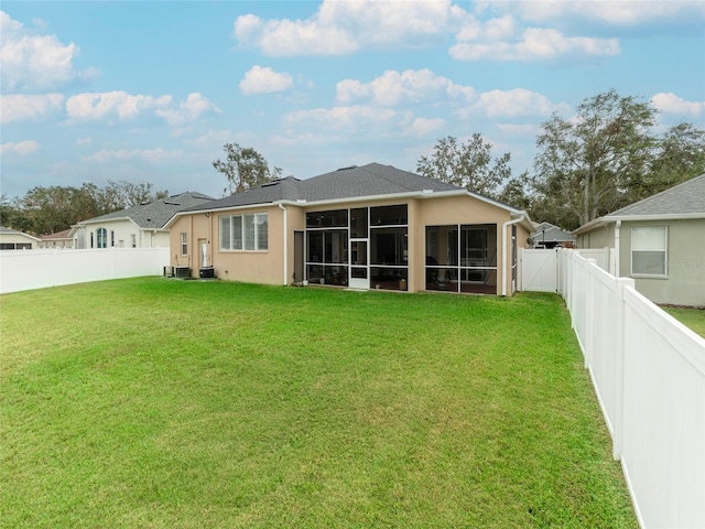 rear view of property featuring a sunroom and a yard