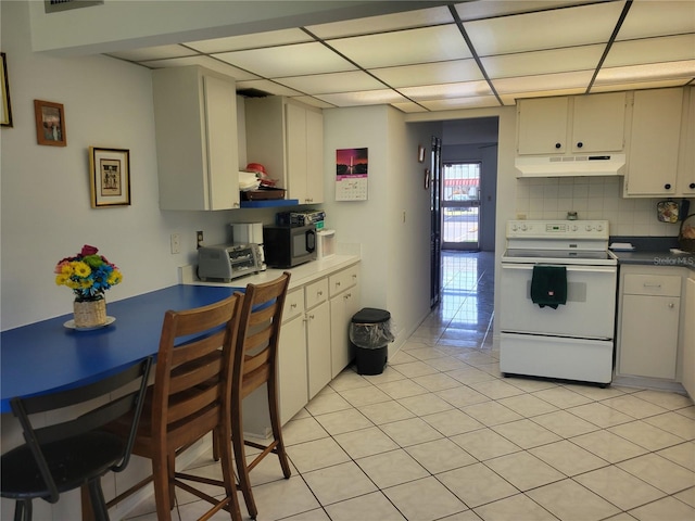 kitchen featuring electric stove, backsplash, a paneled ceiling, and light tile patterned flooring