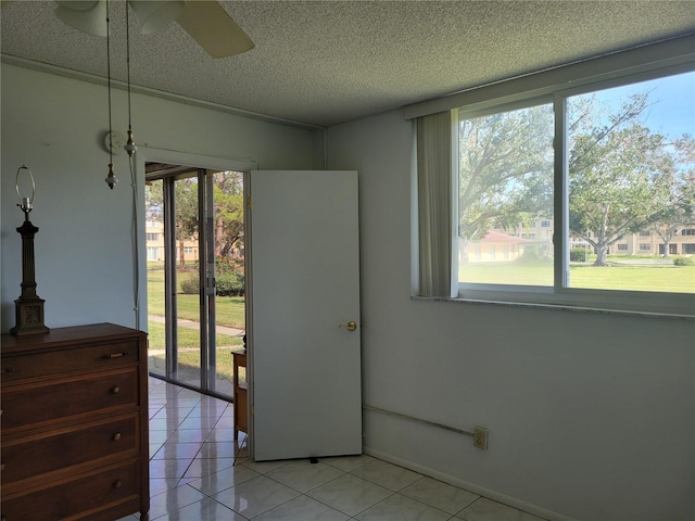 interior space with light tile patterned flooring, access to outside, ceiling fan, and a textured ceiling