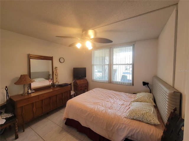 tiled bedroom with ceiling fan and a textured ceiling