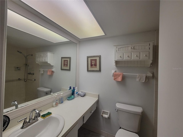 bathroom with vanity, toilet, and a tile shower