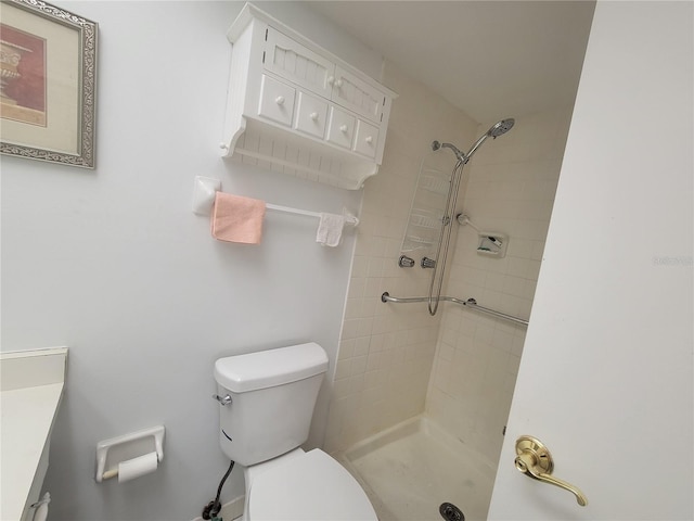 bathroom featuring vanity, a tile shower, and toilet