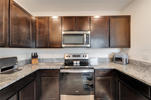 kitchen featuring light stone counters, dark brown cabinets, and stainless steel appliances