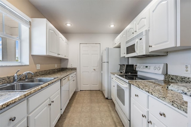 kitchen with white cabinets, white appliances, light stone countertops, and sink