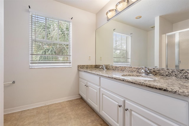 bathroom with tile patterned floors, a wealth of natural light, vanity, and a shower with shower door