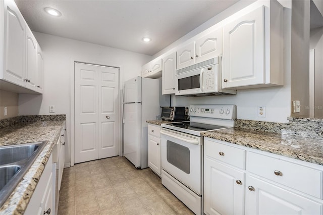 kitchen featuring light stone countertops, white appliances, white cabinetry, and sink