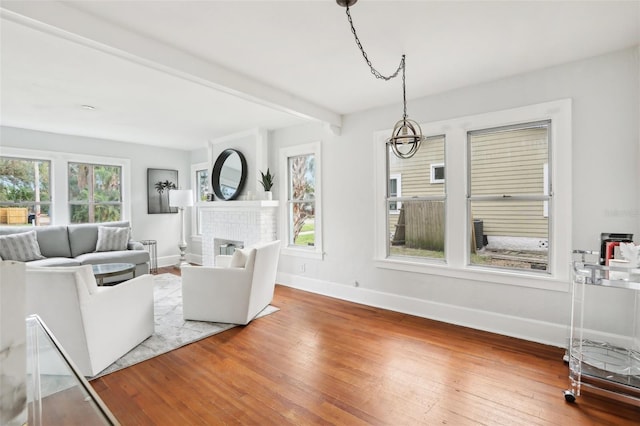 living room with a brick fireplace, hardwood / wood-style floors, and beamed ceiling