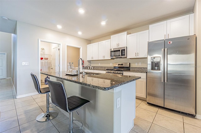 kitchen featuring a kitchen island with sink, white cabinets, and stainless steel appliances