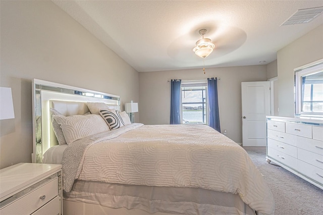 carpeted bedroom with a textured ceiling, multiple windows, lofted ceiling, and ceiling fan