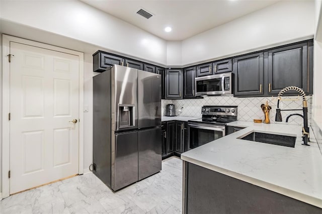 kitchen with light stone countertops, sink, backsplash, and stainless steel appliances