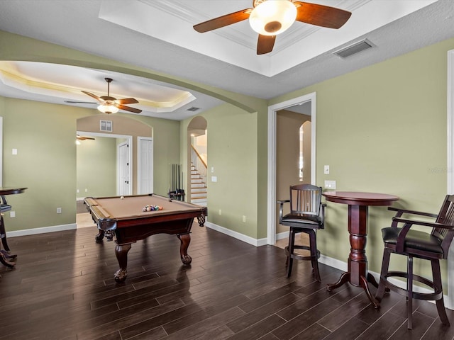 game room with ornamental molding, a raised ceiling, and dark wood-type flooring