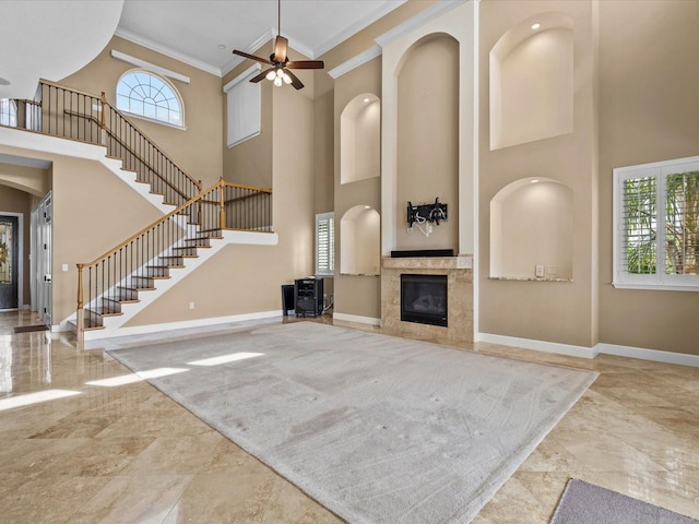 unfurnished living room featuring ceiling fan, a towering ceiling, and ornamental molding