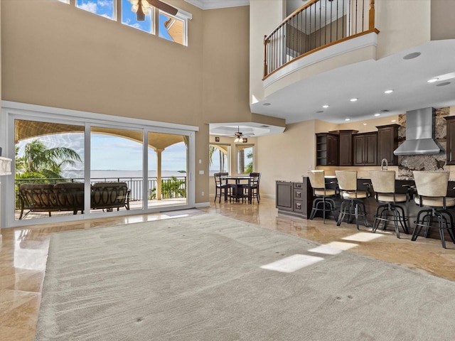 living room featuring ceiling fan, a healthy amount of sunlight, and a towering ceiling