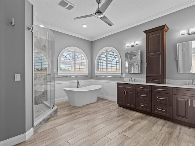 bathroom with plus walk in shower, vanity, hardwood / wood-style flooring, and crown molding