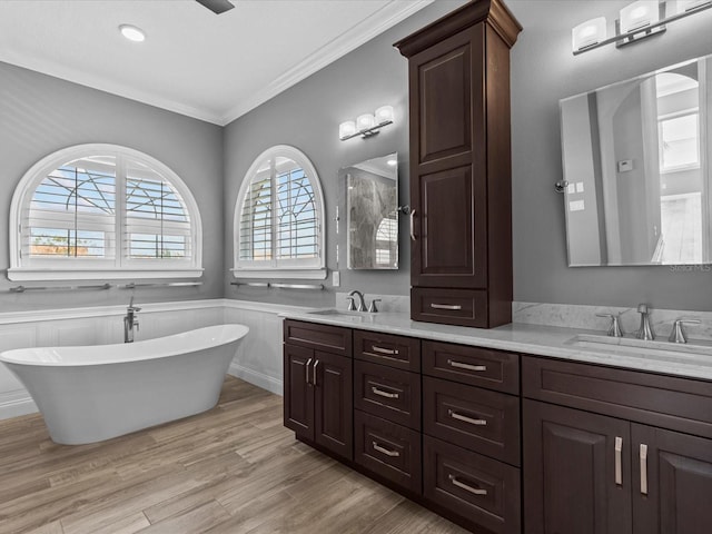 bathroom with vanity, hardwood / wood-style flooring, crown molding, and a tub