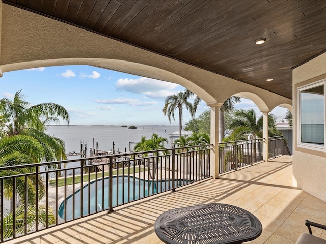 view of patio featuring a water view, a fenced in pool, and a balcony