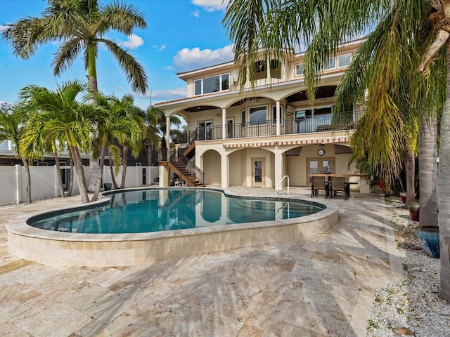 back of house featuring a fenced in pool, a balcony, and a patio