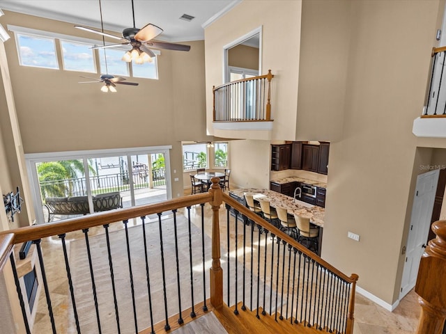 staircase with a towering ceiling, plenty of natural light, and crown molding