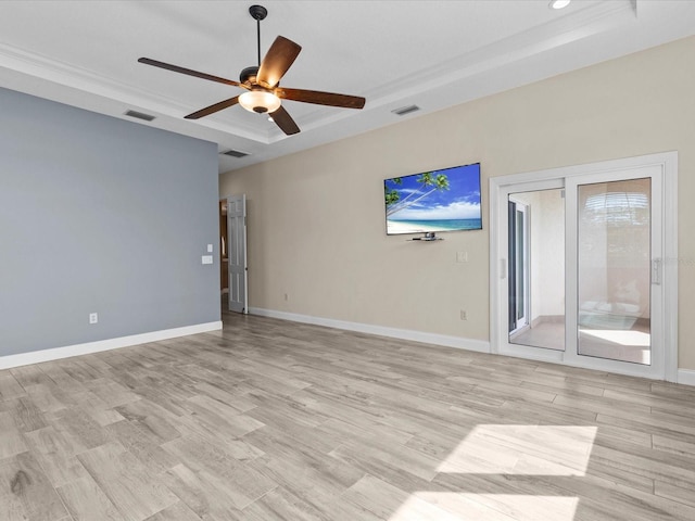 spare room with a tray ceiling, light hardwood / wood-style flooring, and ceiling fan