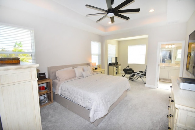 carpeted bedroom with a raised ceiling, ceiling fan, and ensuite bathroom