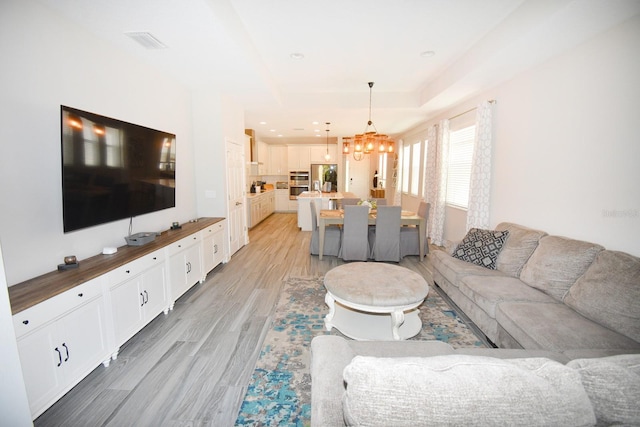 living room with light wood-type flooring and a notable chandelier