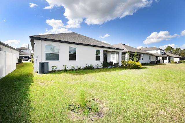 rear view of property featuring central AC and a lawn