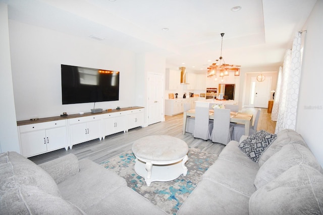 living room featuring light wood-type flooring and a notable chandelier