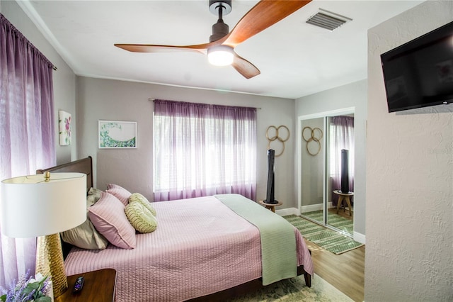 bedroom featuring hardwood / wood-style flooring, ceiling fan, and a closet