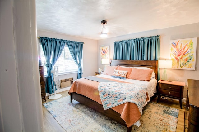 bedroom with wood-type flooring and an AC wall unit